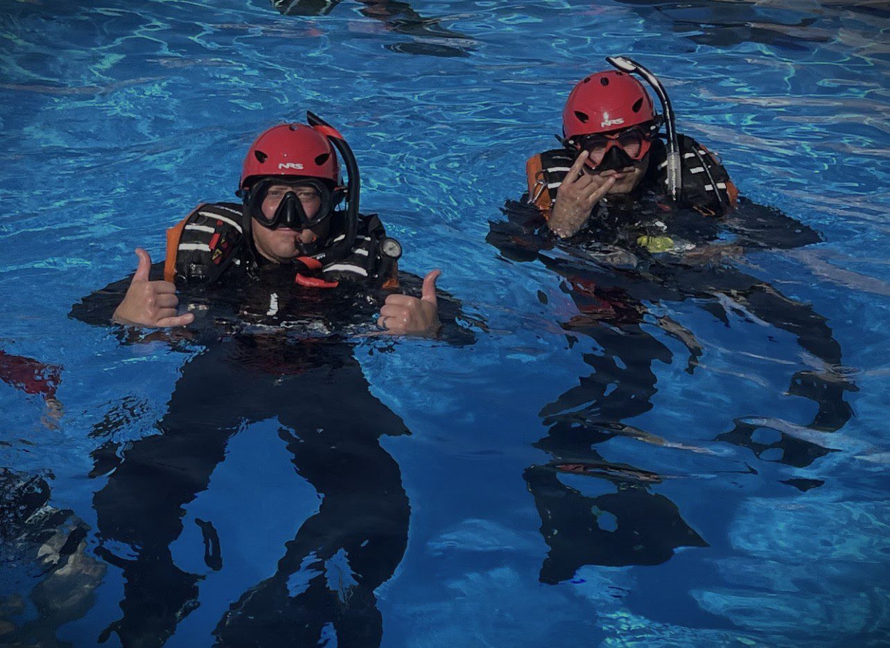 Two people in scuba gear floating on a body of water.