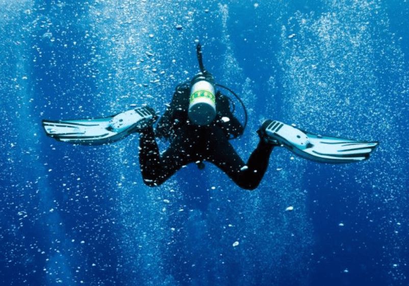 A diver under water with full suit and oxygen tank